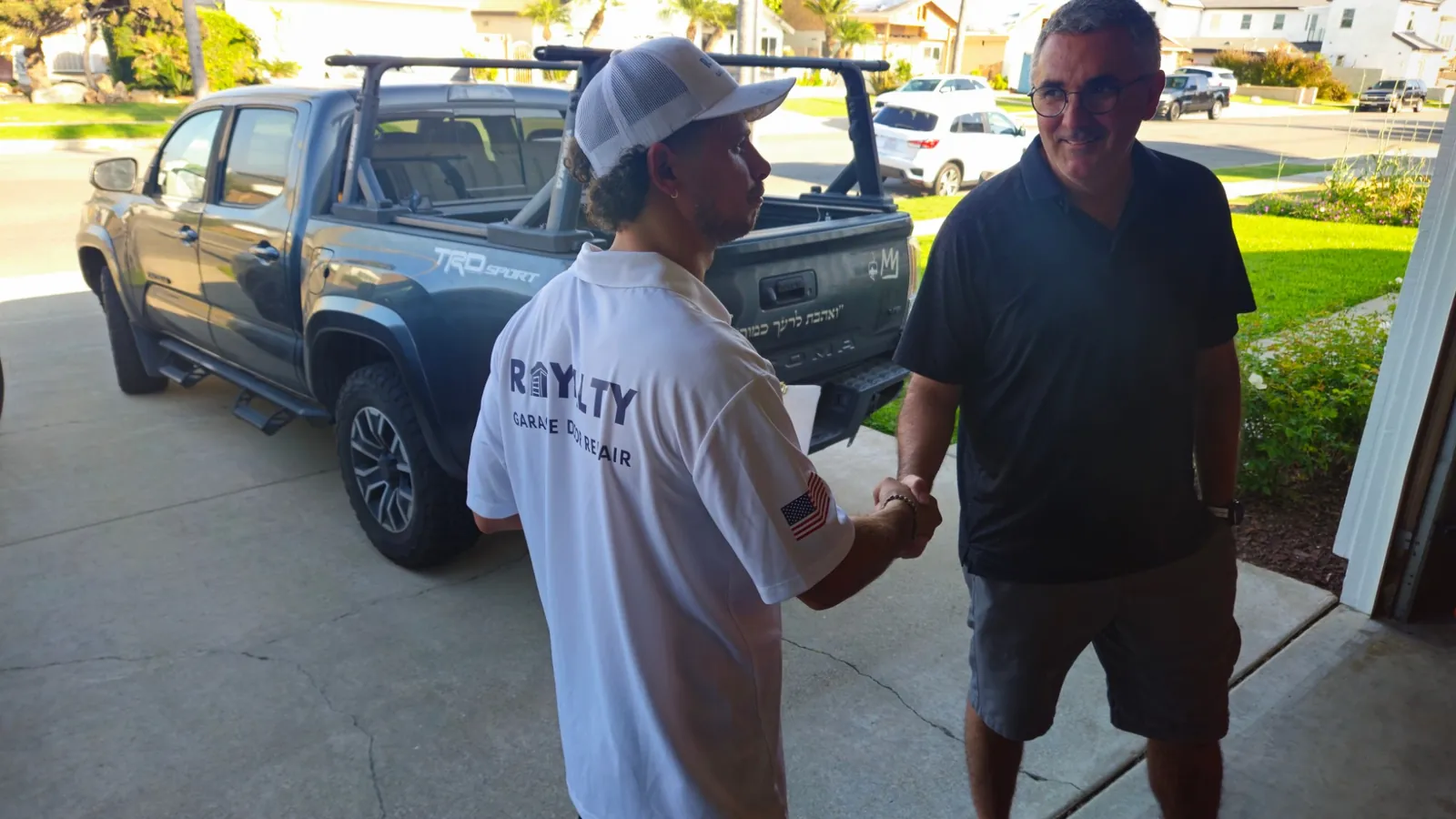 Royalty technician shaking hands with a homeowner in the driveway beside the service truck