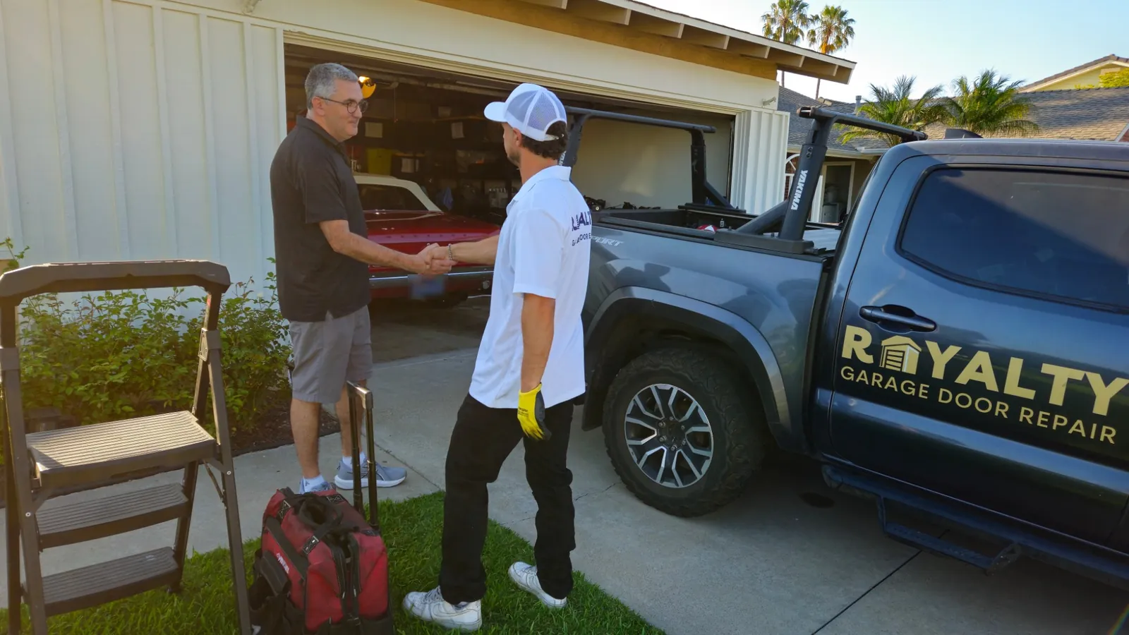 Royalty technician shaking hands with a homeowner in front of an open garage
