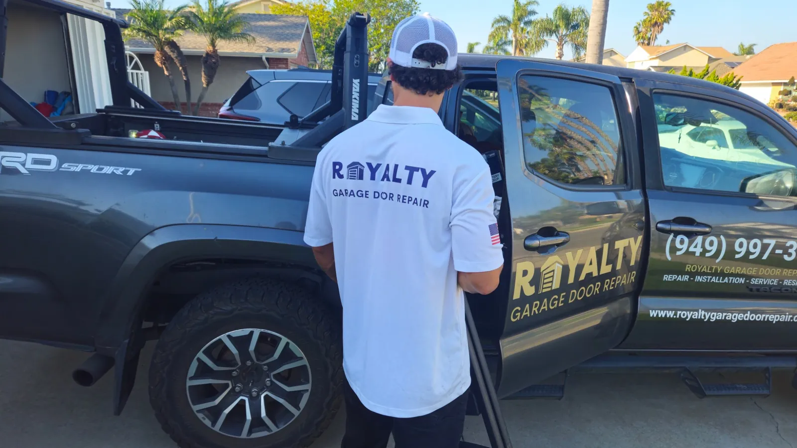 Royalty technician in branded uniform loading equipment at the service truck